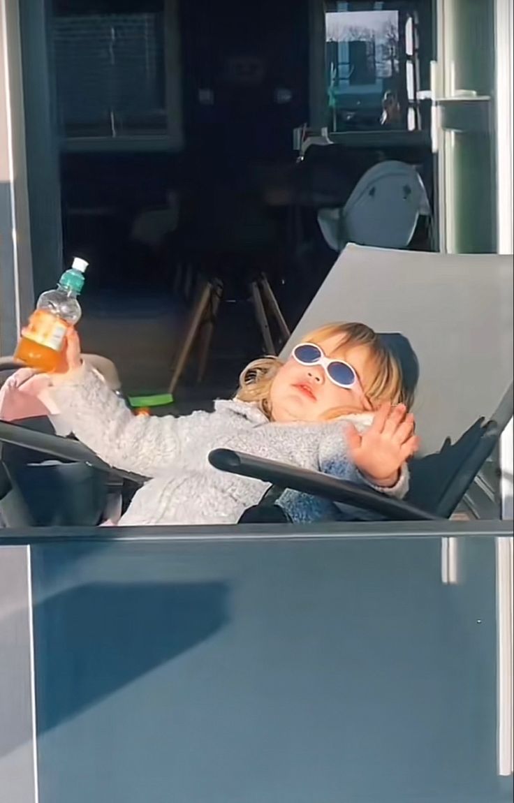 A child relaxing in the sun holding a drink